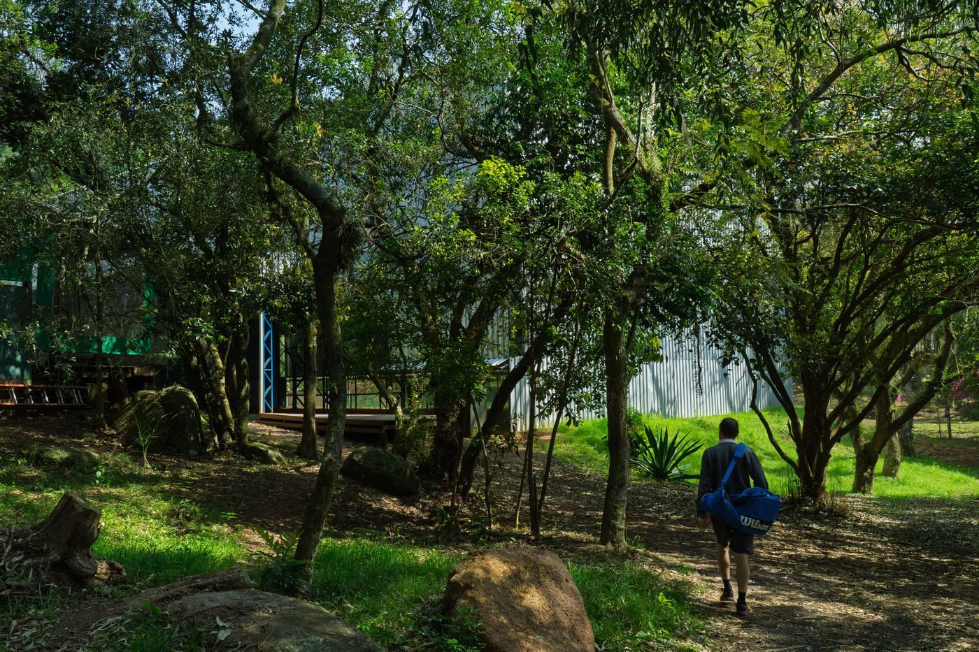 Uma pessoa com a bolsa de tênis caminhando entre as árvores