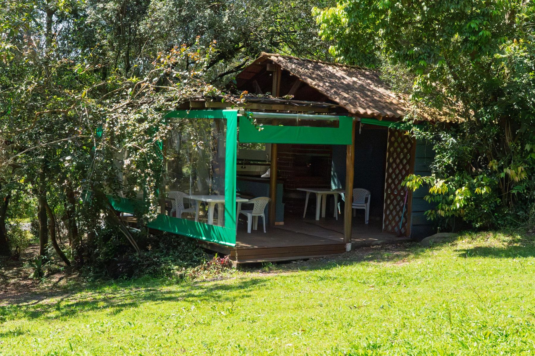 O quiosque, com deck e mesas, entre as árvores